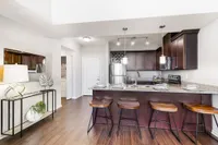 Elegant kitchen space featuring granite countertops, modern stainless steel appliances, and chic pendant lighting with a cozy breakfast bar and stylish wooden stools.