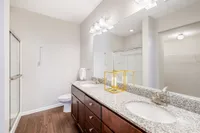 Elegant bathroom featuring a double granite vanity, modern lighting, and a spacious glass-enclosed shower.