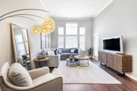 Elegant living room with modern decor, featuring a cozy sectional sofa, stylish pendant lighting, and a sleek entertainment center with a flat-screen TV.