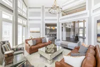 Elegant living room with high ceilings, large windows, cozy leather sofas, and a chic mirrored coffee table, perfect for entertaining.