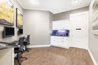 Modern apartment workspace with two computer stations, elegant wood flooring, and a sleek cabinet for storage.