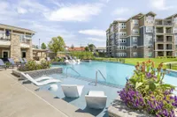 Luxurious apartment complex with a pristine swimming pool, surrounded by lush landscaping and modern architecture.