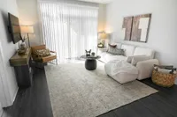 Bright and inviting living room with elegant decor, featuring a cozy white sofa, stylish accent chairs, a chic coffee table, and abundant natural light through vertical blinds.