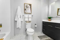 Elegant modern bathroom featuring sleek fixtures, stylish vanity, wall art, and cozy ambiance.