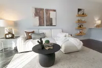 Elegant living room showcasing a plush white sectional, chic artwork, and stylish shelves with decorative accents creating a cozy, inviting ambiance.
