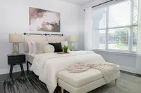 Bright and airy bedroom featuring a cozy bed, elegant decor, and expansive window with garden view.