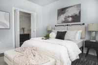 Inviting bedroom with modern decor, featuring a plush bed, stylish lamps, and a spacious walk-in closet.