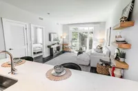 Bright, contemporary open-plan living room with stylish decor, featuring a cozy seating area, modern kitchen space, and a view of the lush garden through large sliding doors.