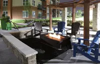 Inviting outdoor patio with cozy fire pit, Adirondack chairs, and hammock, ideal for relaxing evenings under a stylish pergola.