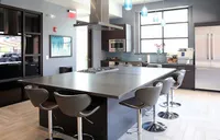 Modern kitchen design featuring a spacious island with sleek bar stools, stainless steel appliances, and elegant pendant lighting.