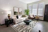 Chic living room with modern decor, natural light, and cozy seating in a stylish apartment.