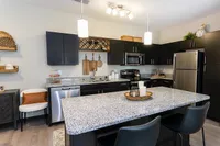 Modern kitchen with granite countertops, sleek black cabinets, and stainless steel appliances, offering a stylish and functional space for culinary creations.