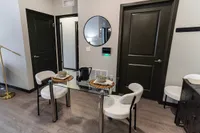 Chic dining area with elegant glass table and modern decor, highlighted by cozy seating and stylish black doors.