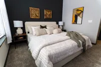 Cozy and elegant bedroom with plush bedding, stylish lamps, and modern artwork, offering a serene retreat.