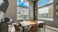 Bright, modern office space with large windows, elegant wooden table, and comfortable chairs, offering a perfect setting for productivity and creativity.