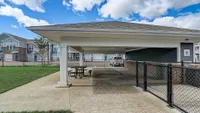 Inviting apartment complex showcasing outdoor picnic area and ample parking space, set against a blue sky with modern architecture.