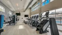 Bright and modern fitness center with top-of-the-line exercise equipment, large windows, and sleek flooring, offering an invigorating workout experience.