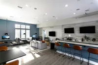 Modern community lounge with a bright, spacious interior, featuring sleek seating, ample natural light, and a stylish bar area with high stools.