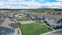 Vibrant aerial view of a modern apartment complex with beautiful landscaped gardens, ample parking, and scenic surroundings.