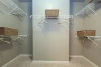 Spacious walk-in closet with sleek wire shelving and elegant woven baskets for organized and stylish storage.
