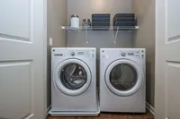 Modern laundry room with sleek washer and dryer set, featuring stylish shelving for organized storage.
