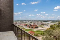 Stunning panoramic view from the apartment balcony showcasing a vibrant cityscape and serene river under a bright blue sky.