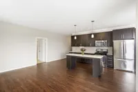 Modern kitchen with sleek dark cabinets, stainless steel appliances, and elegant hardwood flooring.