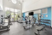 Bright and modern fitness center featuring state-of-the-art cardio machines, free weights, and a spacious workout area.