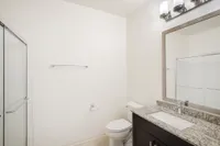 Modern bathroom with elegant granite countertop, sleek fixtures, and a spacious glass shower.
