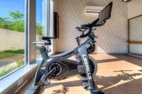 Sunlit fitness room with a modern exercise bike overlooking a lush green outdoor area.