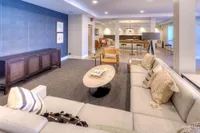 Sophisticated living room with plush sofas, modern decor, and open layout leading to dining area, perfect for entertaining guests.