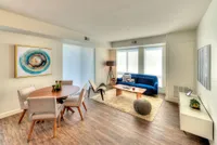 Modern living room with elegant decor featuring a sleek blue sofa, stylish dining area, and warm wooden flooring.