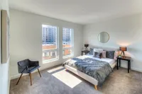 Bright and modern bedroom with large windows, stylish decor, and city views. Cozy ambiance perfect for relaxation.