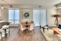 Modern open-plan living area with stylish furnishings, featuring a round wooden dining table, cozy plush rug, and elegant decor accents.