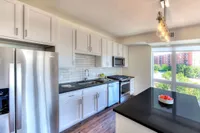 Modern kitchen with sleek stainless steel appliances, white cabinetry, and a large window flooding the space with natural light.