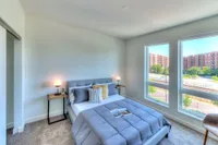 Bright and cozy bedroom with a modern bed, stylish side tables, and large windows offering a stunning city view.