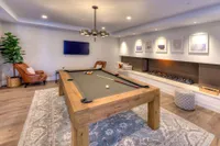 Elegant game room with a stylish pool table, cozy seating, modern wall art, and ambient lighting.