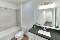 Modern bathroom with sleek fixtures, large mirror, and elegant tile accents, offering a bright and refreshing atmosphere.