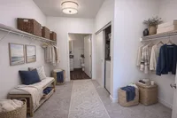 Chic walk-in closet featuring stylish woven baskets, elegant wall art, and ample hanging space. Cozy bench and textured carpet complete the serene atmosphere.