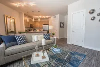 Modern open-concept living area with elegant lighting, featuring a cozy sofa and chic kitchen island, perfect for entertaining.