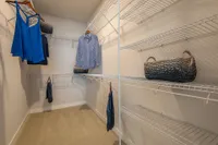 Spacious walk-in closet with elegant wire shelving and stylish wicker baskets, offering ample storage space.