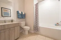 Modern bathroom featuring elegant wood cabinetry, stylish tile flooring, and a soothing bathtub with a patterned shower curtain.