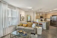 Modern open-concept living room and kitchen with sleek decor, natural light, and elegant finishes.