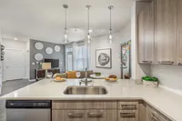 Modern kitchen with elegant light fixtures and stylish living area featuring contemporary decor and abundant natural light.