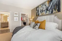 Elegant bedroom with plush bedding, vibrant artwork, and a spacious walk-in closet, offering a luxurious and cozy atmosphere.