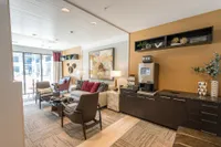 Inviting and modern living room with stylish decor, comfortable seating, and a sleek coffee station, bathed in natural light from large windows.