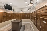 Elegant mailroom featuring warm wooden finishes, multiple secure mailboxes, and modern lighting fixtures for an upscale apartment complex.