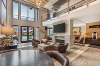 Luxurious living area featuring high ceilings, stylish modern furniture, and expansive windows overlooking a vibrant outdoor pool area.