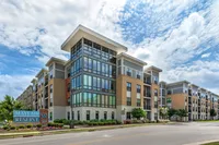 Impressive modern apartment complex with large windows and sleek architectural design under a picturesque sky.