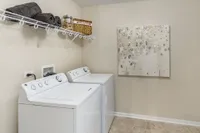 Modern laundry room with sleek washer and dryer, elegant shelving, and stylish wall art.